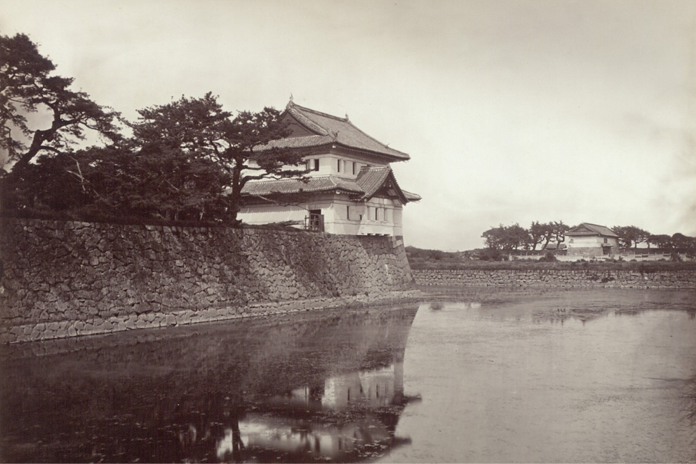 Fotografie eines japanischen Palastgebäudes vor einem Burggraben mit Wasser
