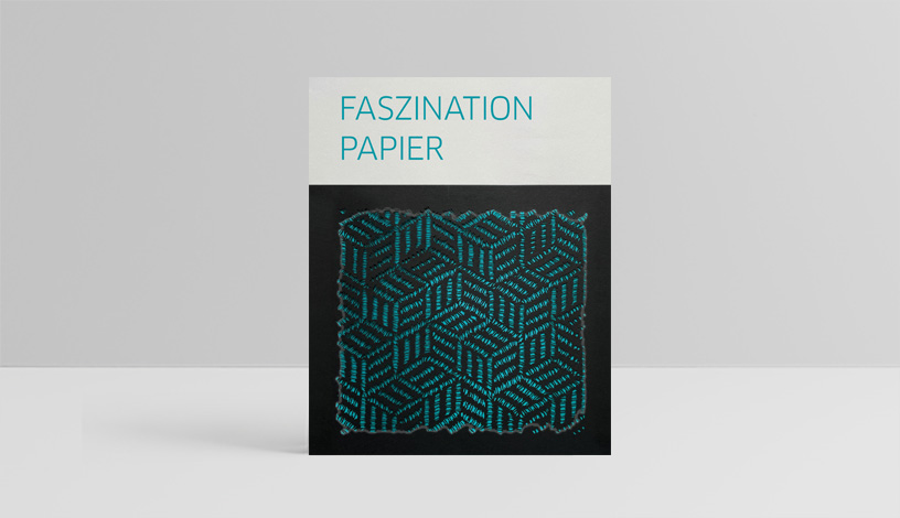 Der Katalog zur Ausstellung Faszination Papier (in türkischer Schrift), darunter ein gestanztes, schwarzes Bild mit türkisem Hintergrund.